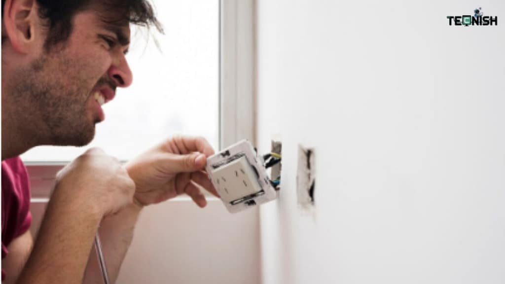 Person safely removing an old light switch with labeled wires using a screwdriver for smart switch installation