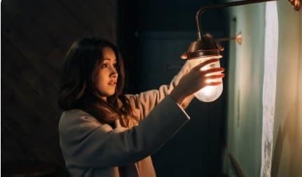 Person using smartphone and voice assistant to control smart light switch remotely at home